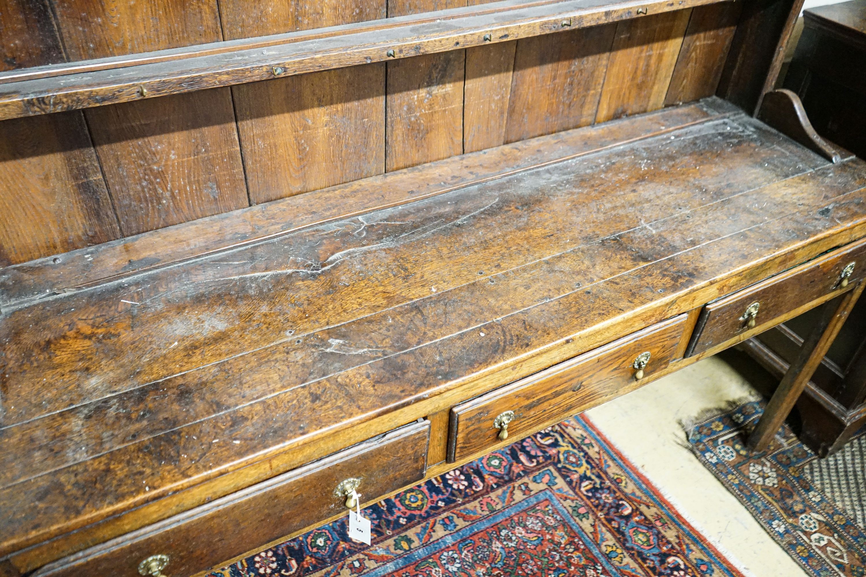 A George III oak dresser, with two shelf rack and three long drawers, on chamfered legs, width 167cm, depth 49cm, height 193cm